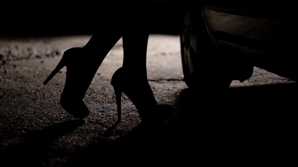 Une femme portant des talons hauts est sur le point de monter dans une voiture.