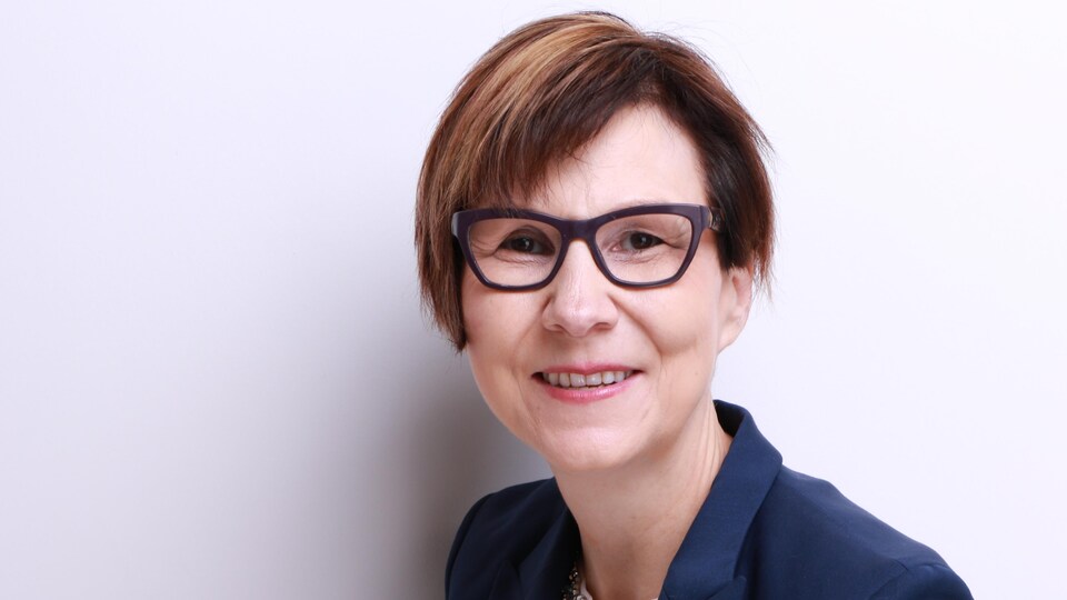 Une femme de face avec des lunettes qui regarde l'objectif.