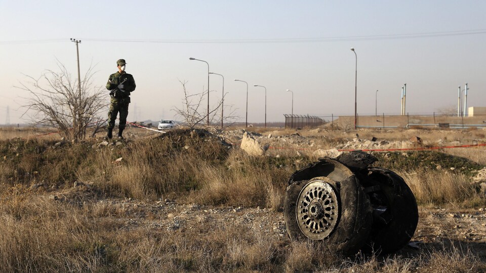 Un officier de police monte la garde alors que l'on voit les débris d'un avion ukrainien qui s'est écrasé à Shahedshahr, au sud-ouest de la capitale Téhéran.