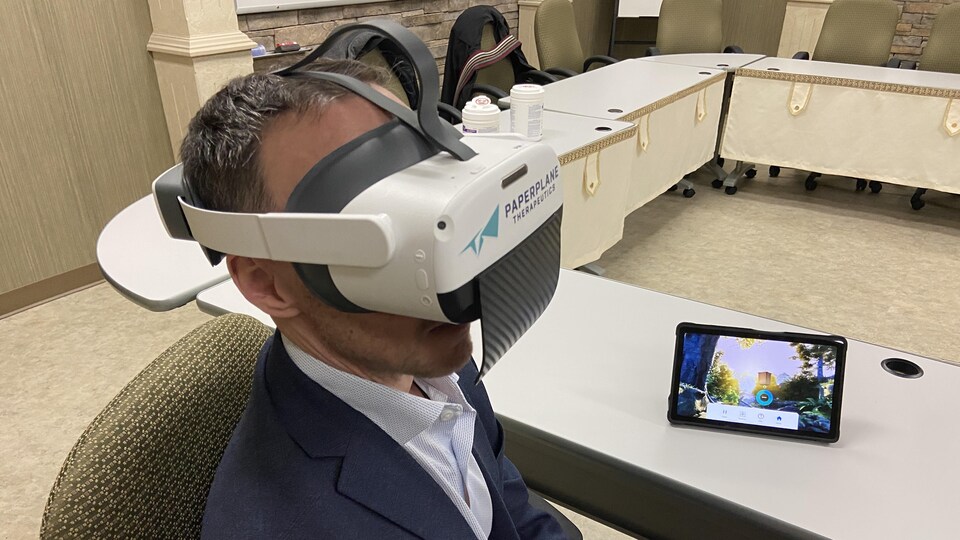 Un homme assis porte un casque de réalité virtuelle.