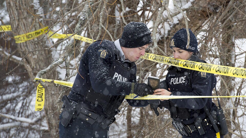 Des policiers consultent des notes sur une scène d'incendie.