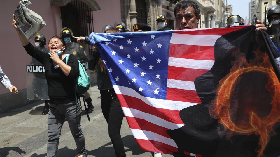 Des manifestants brandissent un drapeau américain orné de la lettre Q, symbole de QAnon.