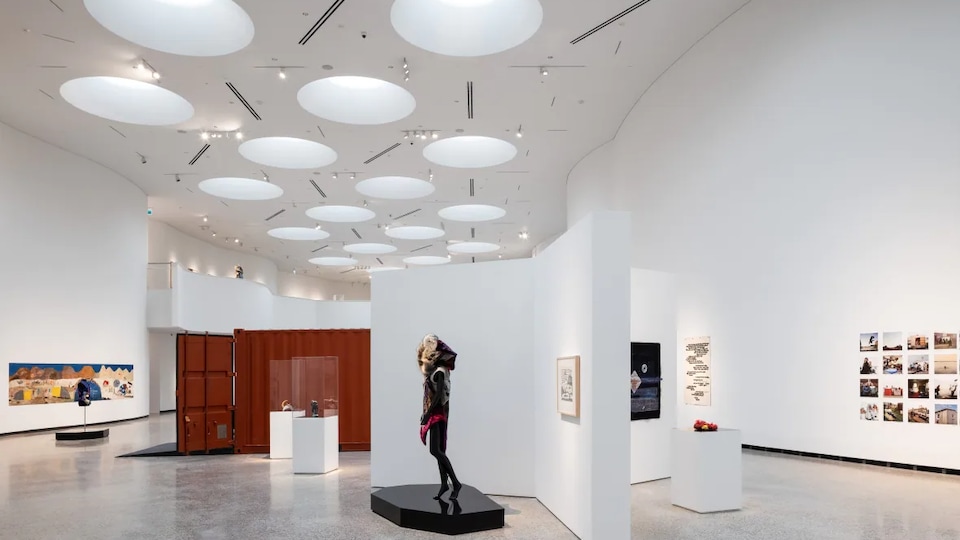 Une salle d'exposition montrant de l'art inuit avec plusieurs puits de lumière au plafond. 