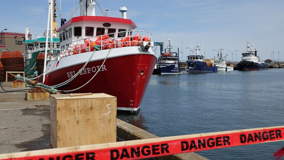 Une barrière où on peut lire « danger » devant un bateau au quai de Cap-aux-Meules.