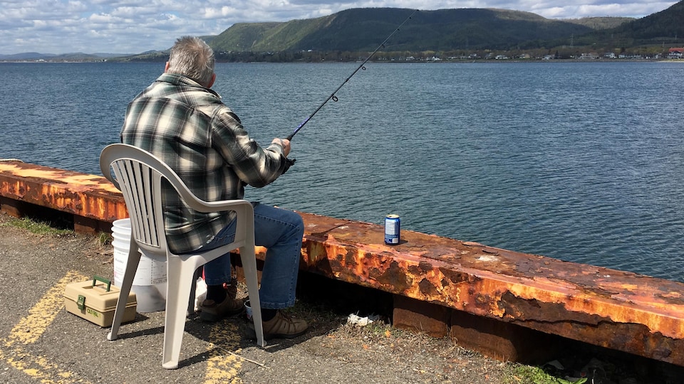 Un pêcheur est installé sur le quai de Carleton-sur-Mer.