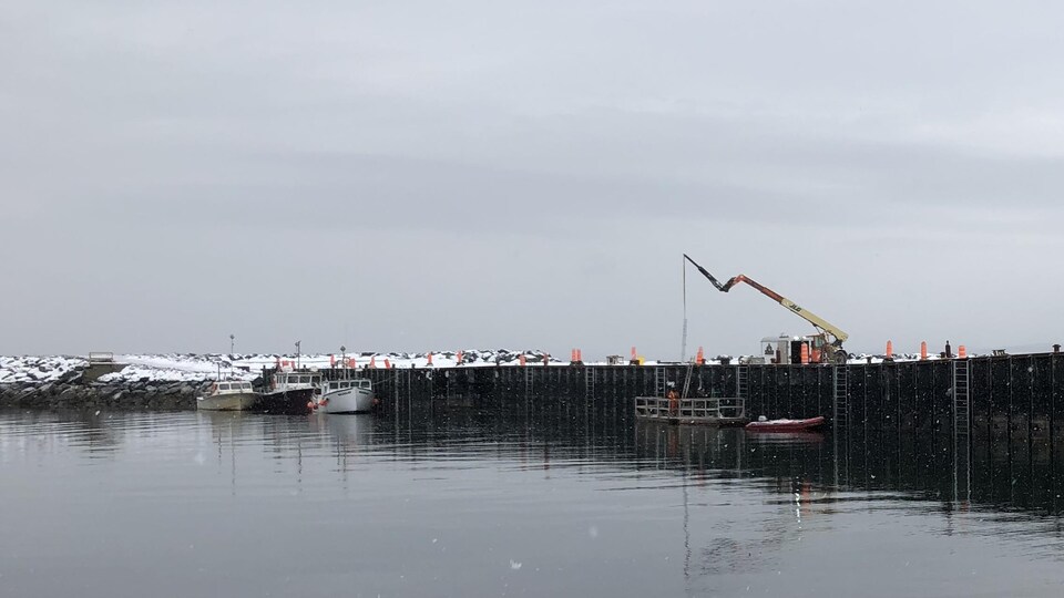 Une grue sur le quai de Carleton avec des travailleurs sur des plateformes flottantes