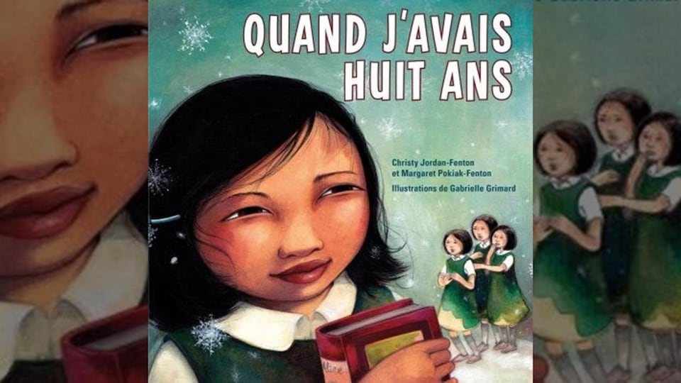 Une fillette tient un livre et trois autres la regardent.