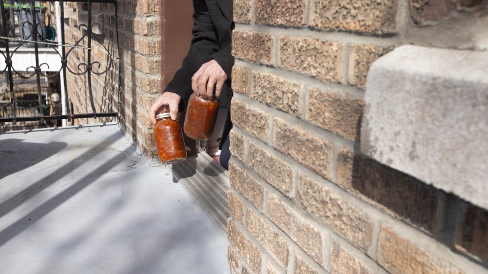 Un homme reçoit de la sauce à spaghetti maison sur le balcon de sa résidence.