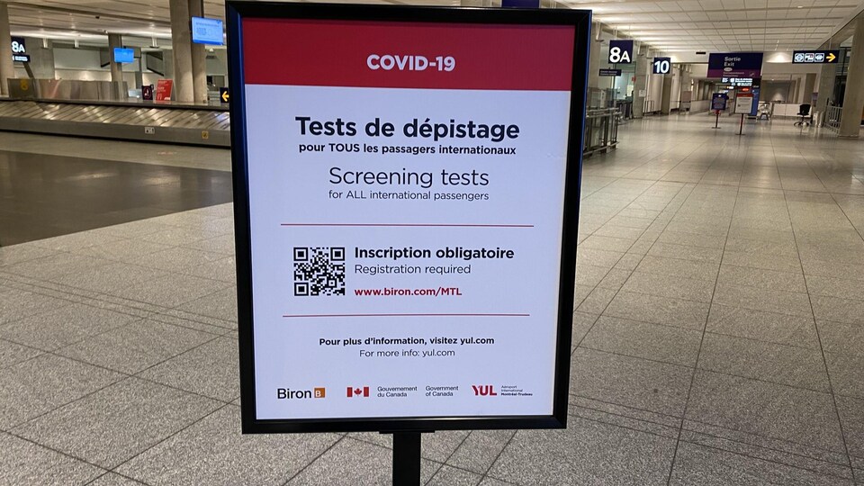 Un panneau dans un aéroport rappelant que les tests de dépistage sont désormais obligatoires pour tous les passagers internationaux