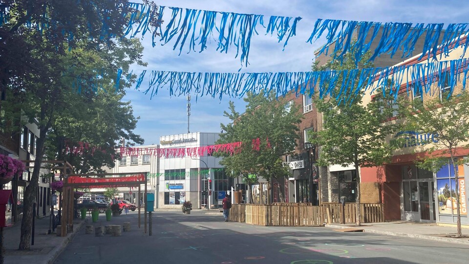 Une rue avec des banderoles accrochées au-dessus, vide de voitures.