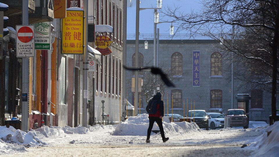 Une personne marche en hiver sur la rue de la Gauchetère Ouest, dans le quartier chinois de Montréal.