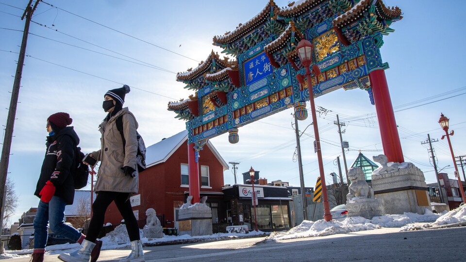 Deux femmes portant le masque dans le quartier chinois d'Ottawa. Derrière elle, on voit l'Arche qui indique l'entrée du quartier chinois.