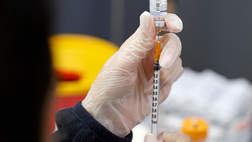 Une personne aspire dans une seringue une dose de vaccin contre la COVID-19.
