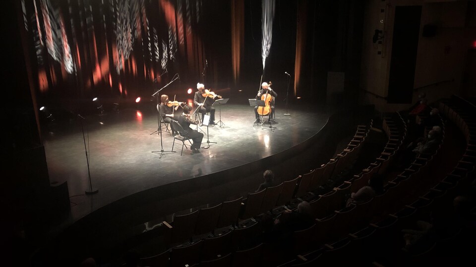 Quatre musiciens jouent un morceau devant un public restreint.