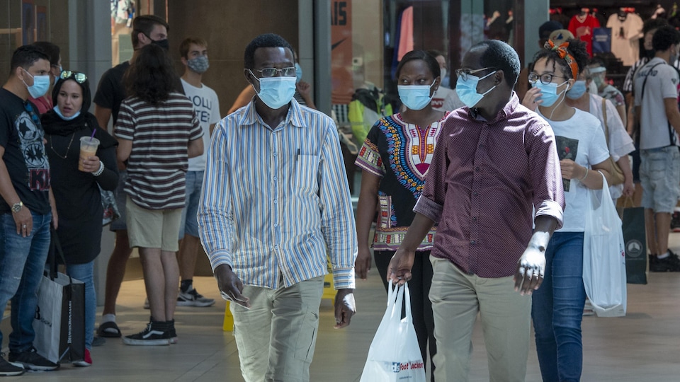 Des personnes portant des masques marchent dans un centre commercial.