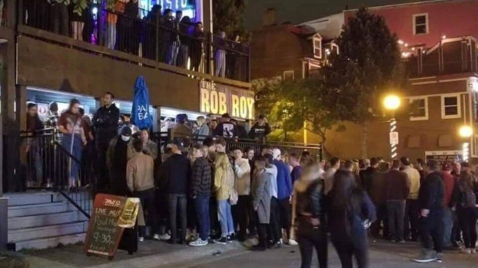 Des gens font la queue à l'extérieur d'un bar.