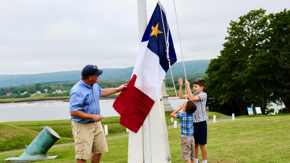 Andrew et Arthur Hebert s'apprêtent a hisser le drapeau acadien au mât du Fort-Anne.