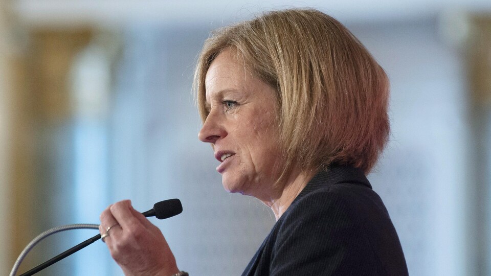 La première ministre de l'Alberta, Rachel Notley, est debout devant un micro et lève la main gauche lors d'un discours à Ottawa.