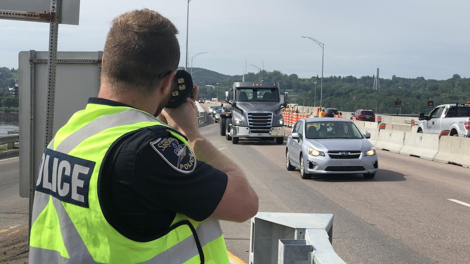 Un policier regarde dans un radar pour vérifier la vitesse des voitures qui arrivent.