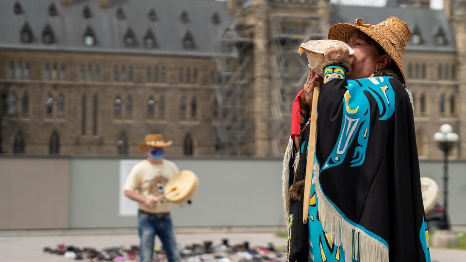 Une femme autochtone en habit traditionnel devant le Parlement à Ottawa.
