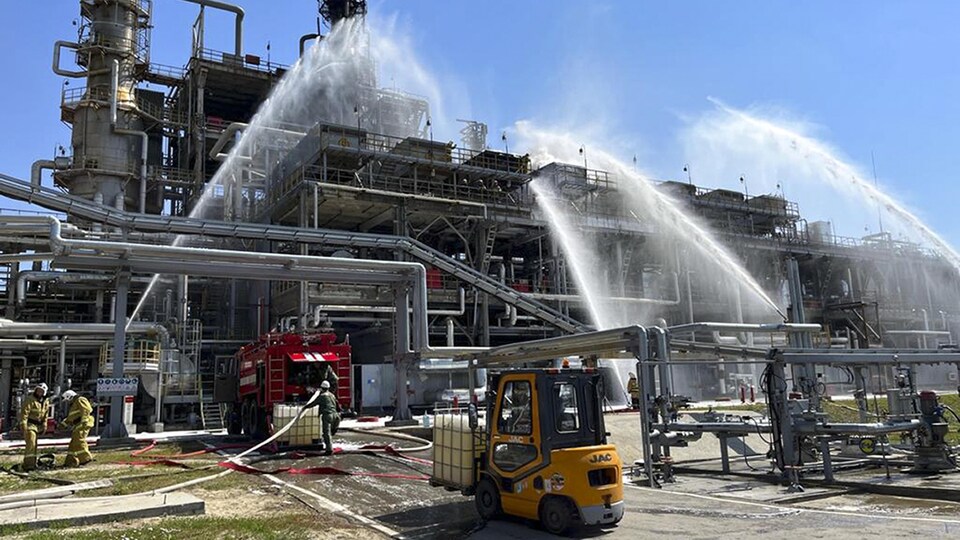 Des pompiers arrosent une usine.