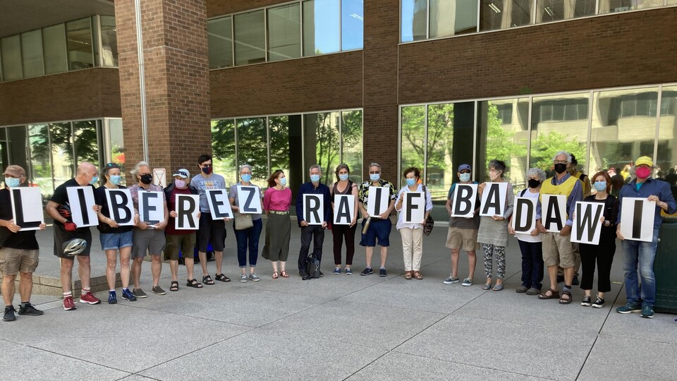 Des gens debout et tenant chacun une pancarte avec comme message : Libérez Raif Badawi.