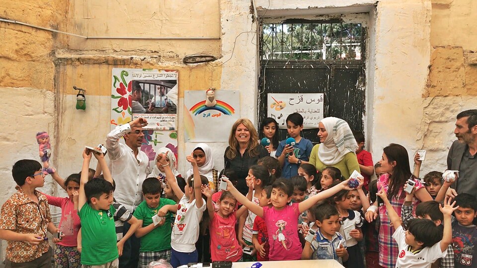 Les enfants réfugiés syriens lèvent les bras de joie après avoir reçu leurs radios.