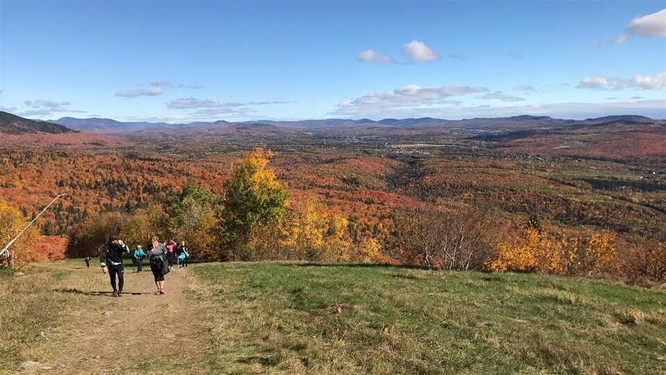 Des randonneurs marchent dans un sentier du mont Sainte-Anne en automne.