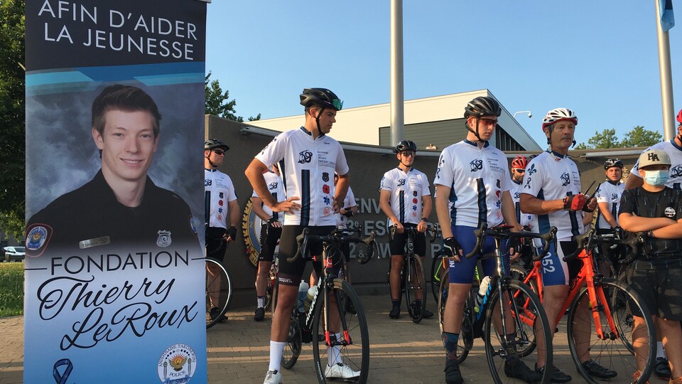 Des cyclistes sur le départ à côté d'une pancarte de Thierry LeRoux.