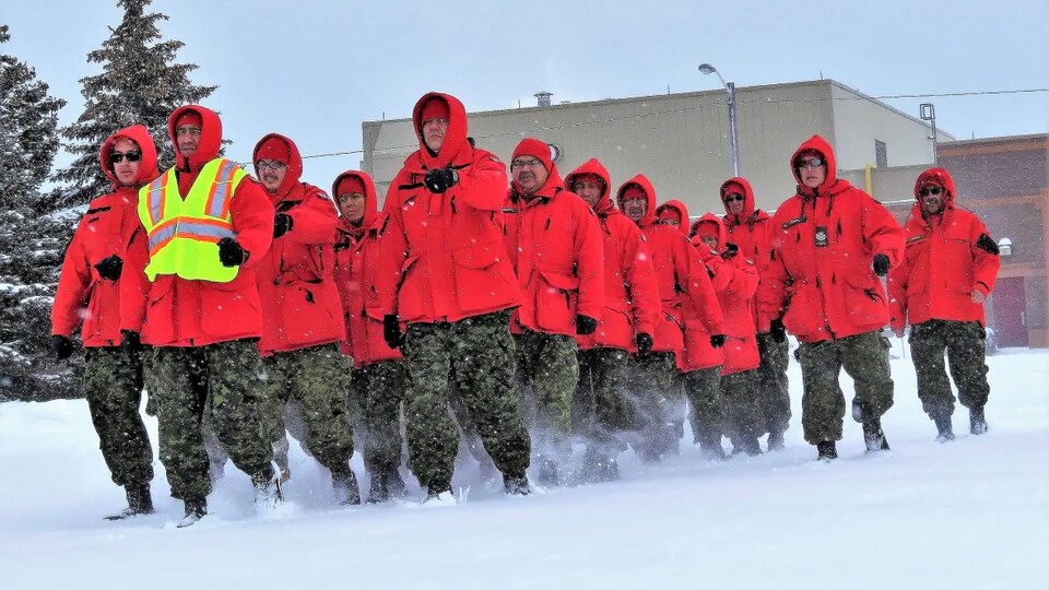 Un groupe habillé en rouge court en peloton dans la neige.
