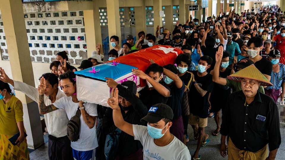 Des personnes font des saluts à trois doigts en portant un cercueil au Myanmar.