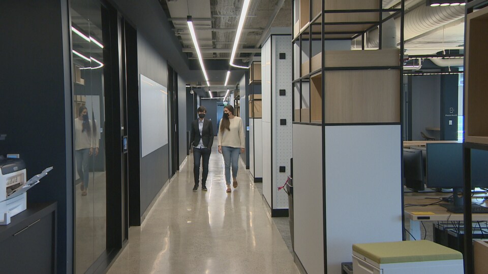 Deux femmes marchent dans un couloir de bureau.