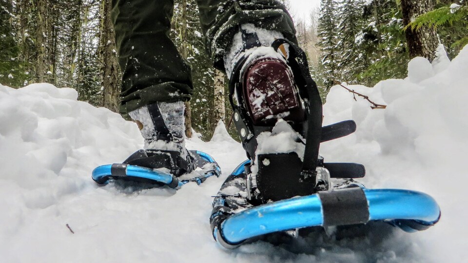 Des jambes qui marchent dans la neige avec des raquettes