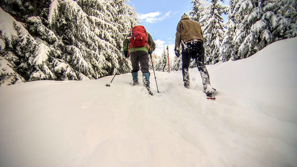 Deux randonneurs en raquettes dans la neige en montagne. 