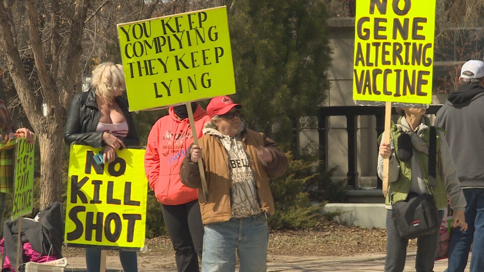 Des gens tenant des pancartes dehors lors d'un rassemblement contre les ordonnances sanitaires en Saskatchewan.