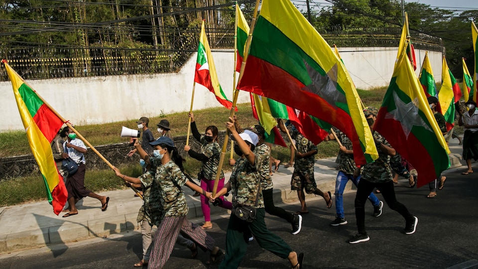 Une vingtaine de partisans proarmée brandissant le drapeau du Myanmar.