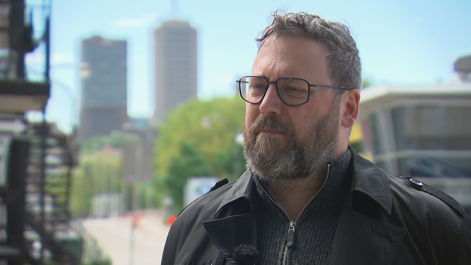 Un homme portant des lunettes discute en entrevue depuis une rue de la ville de Québec.
