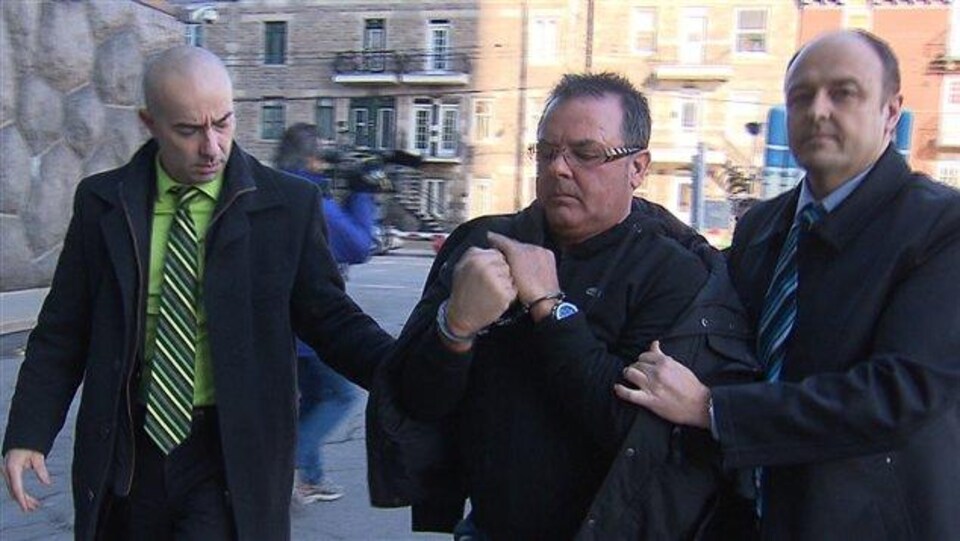 Raynald Desjardins encadré par des policiers.