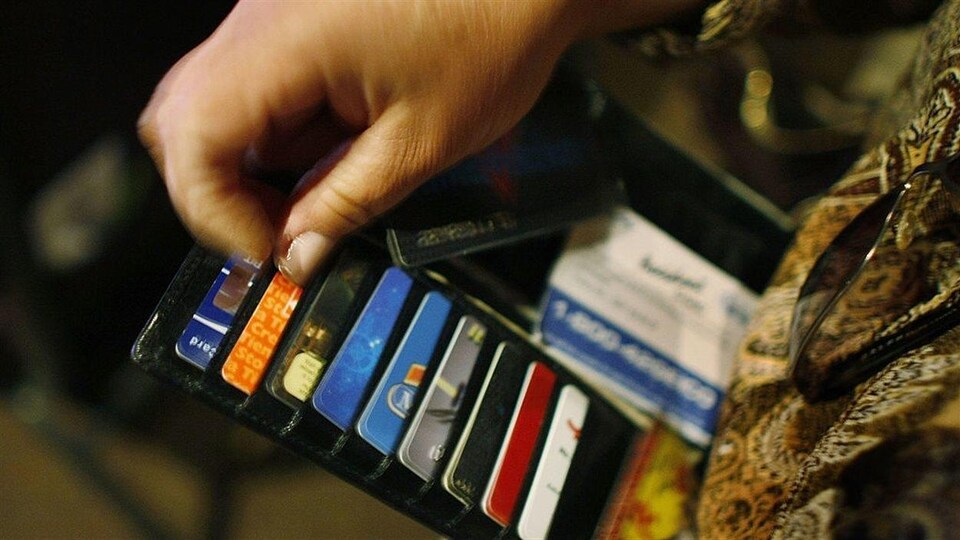 Une femme regarde ses cartes de crédit et d'identification dans son portefeuille.
