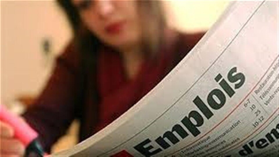 Une femme lit un journal avec des annonces d'emploi.