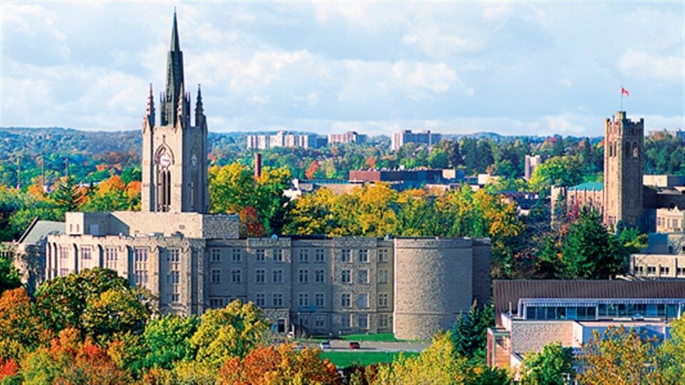 Vue d'ensemble du campus universitaire; un bâtiment surmonté d'une tour de style gothique est au premier plan.