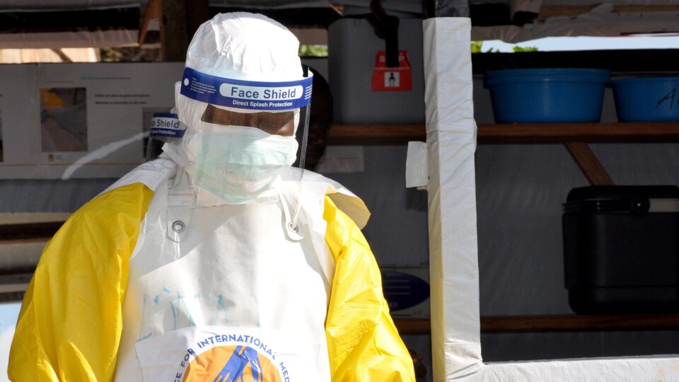 Un travailleur médical porte un uniforme de protection et un masque.