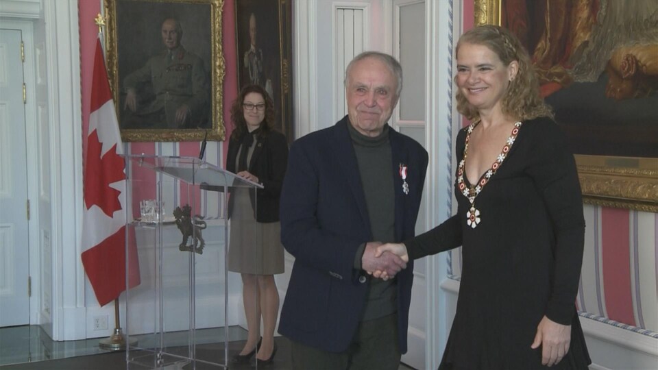 Un homme souriant, Réal Bérard, serre la main d'un femme souriante, Julie Payette.
