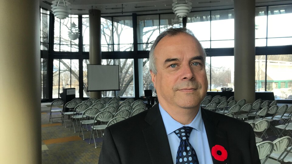 Un homme avec un coquelicot dans une salle de conférence lumineuse.