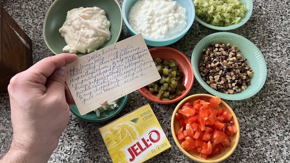 La fiche de recette de la salade de Jell-O et d'autres ingrédients : mayonnaise, fromage cottage, céleri, oignons, cornichons, noix de Grenoble, la boîte de Jell-O et des poivrons rouges.