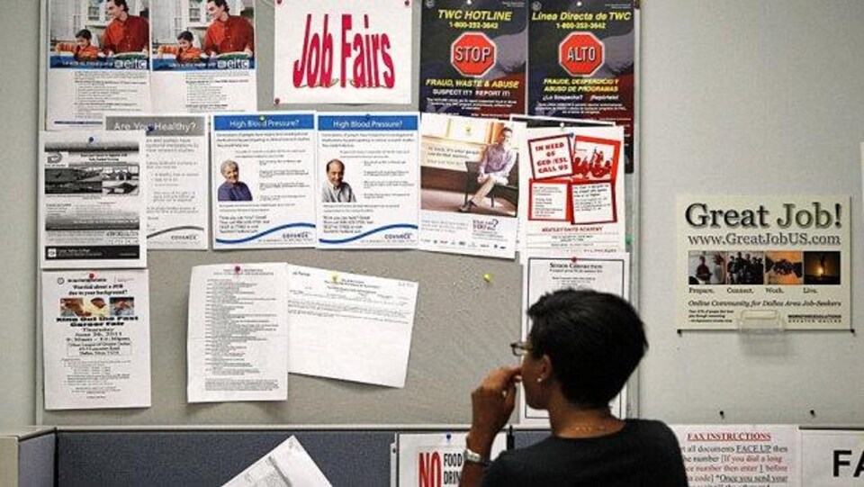 Une dame regarde un tableau d'affichage sur lequel des emplois sont proposés.