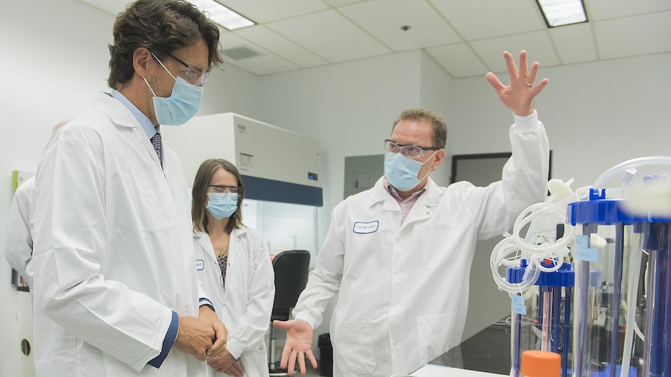 Le premier ministre du Canada Justin Trudeau s'entretient avec des chercheurs en blouse blanche dans un laboratoire.