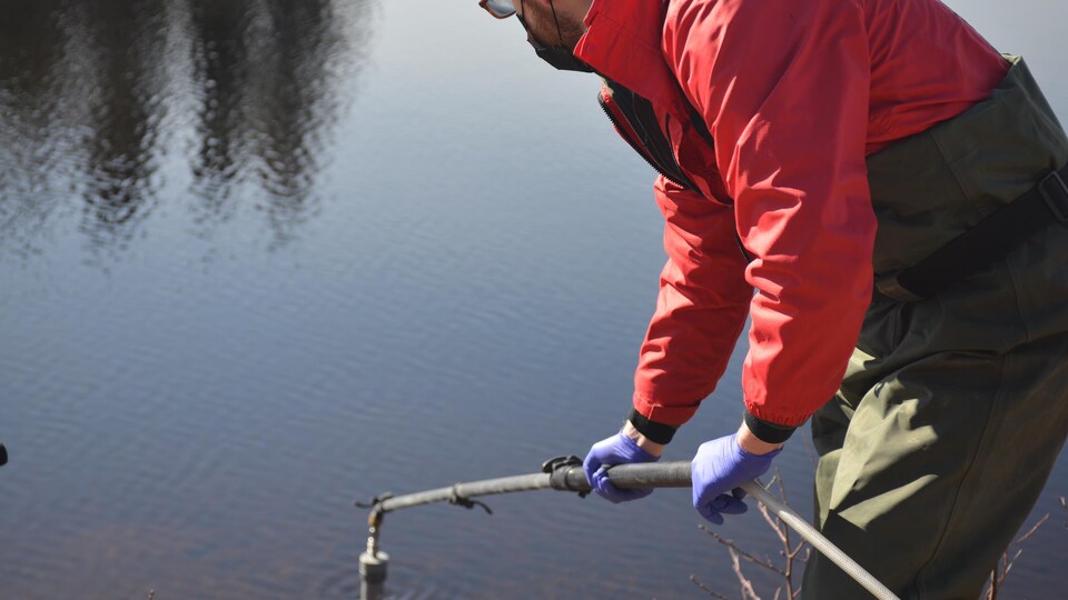 Kyle Knysh tient un baton qui sert à la recolte d'échantillons d'eau.