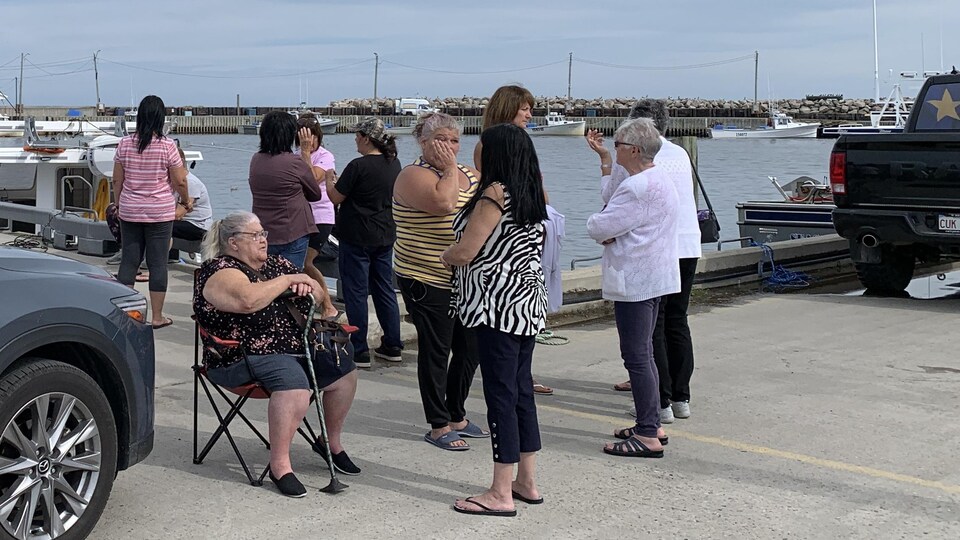 Des gens sont rassemblés au quai de Pointe-Sapin lundi après-midi, alors que des recherches sont en cours pour tenter de retrouver un adolescent porté disparu en mer. 