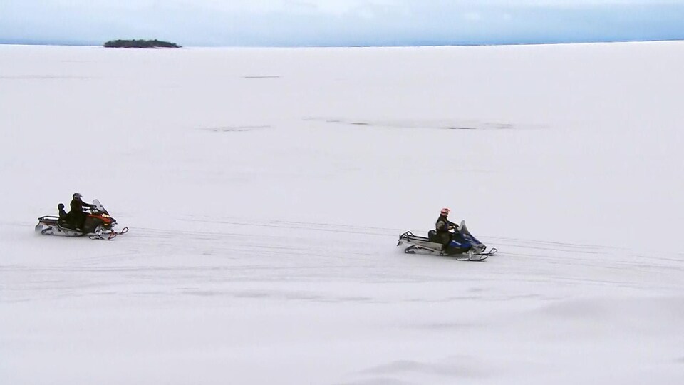 Deux motoneigistes sur un lac couvert de neige
